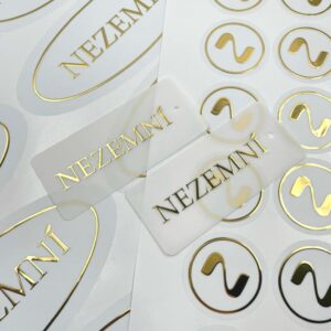 Білі наліпки та бірки із золотим написом NEZEMNÍ.