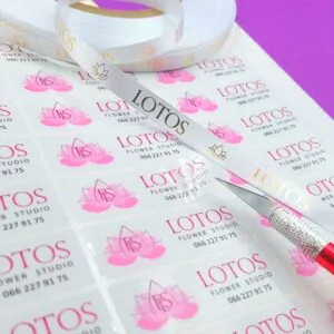 Біла стрічка та прозорі наклейки з логотипом LOTOS, рожева квітка