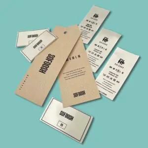 Brown kraft paper hang tags, white fabric care labels with laundry symbols, and rectangular size tags featuring the SOFOOSH brand logo scattered on a teal background.