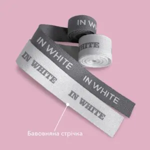 Рулони світлої та темної бавовняної стрічки з білим надрукованим логотипом IN WHITE.